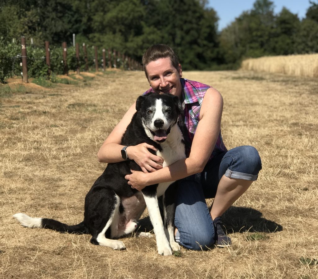 AJ hugging her dog Scuba, a big black and white mutt